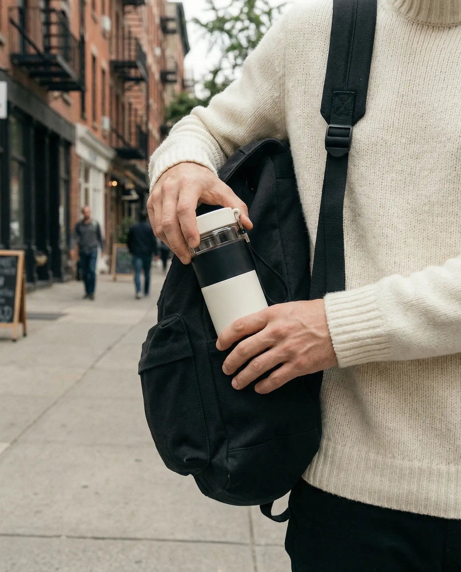 Homme tenant un thermos thé en ville avec sac à dos noir